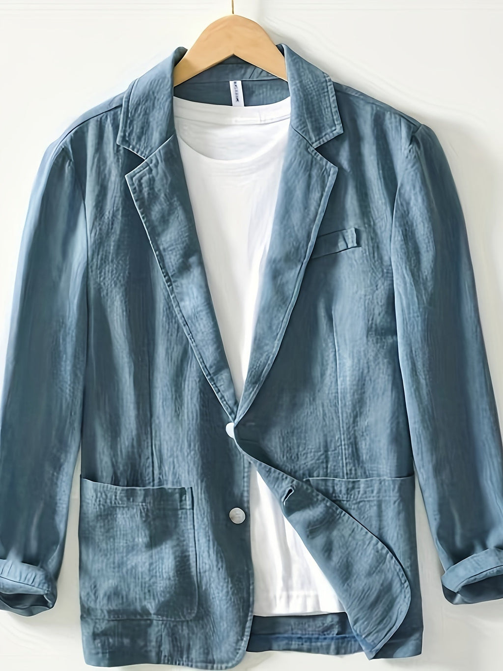 Blue cotton blazer for men with notch lapel and patch pockets, on hanger
