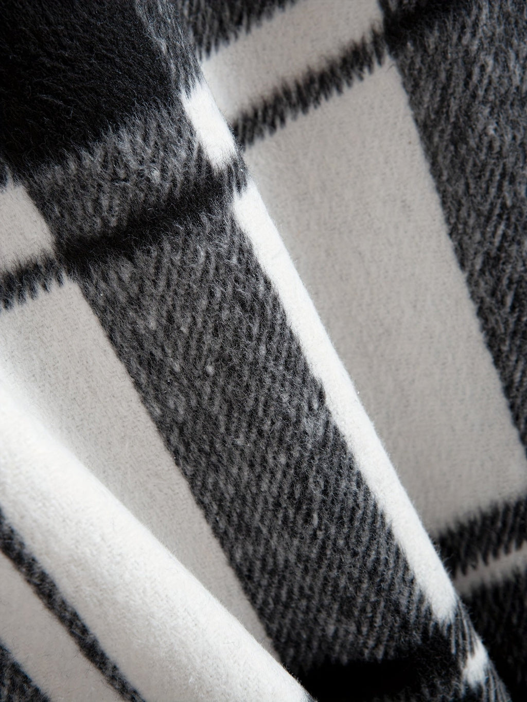 Men's plaid flannel overshirt in black, close-up of the check pattern texture