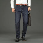 Navy blue stretch straight-fit jeans for men, worn on model with a bag