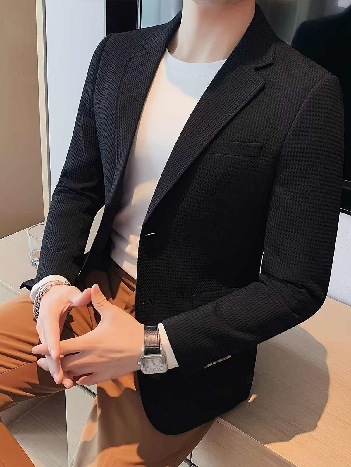 Black waffle knit blazer with a notch lapel, worn open over a casual outfit.